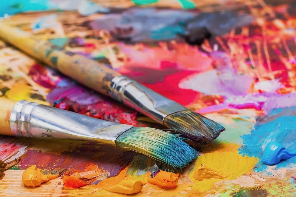 Used brushes on an artist's palette of colorful oil paint used paint brushes on a palette covered with colorful paints.